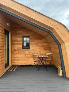 a wooden pavilion with a table and a bench on a deck at Sandy Meadow Escapes in Lairg