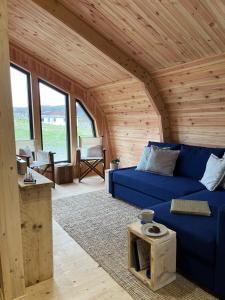 a living room with a blue couch in a cabin at Sandy Meadow Escapes in Lairg