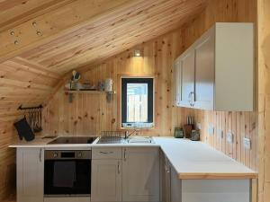 a kitchen with wooden walls and a wooden ceiling at Sandy Meadow Escapes in Lairg