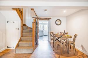une salle à manger avec une table et des chaises et un escalier dans l'établissement Poacher's Cottage, à Dorchester