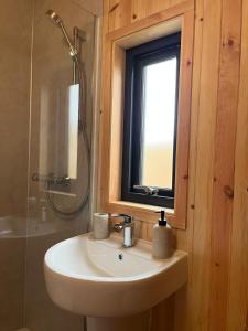 a bathroom with a sink and a window and a shower at Sandy Meadow Escapes in Lairg