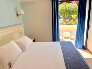 a bedroom with a bed and a large window at Best Western Hotel Blumarea in Castelsardo