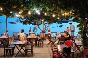 a group of people sitting at tables near the water at Hai Long homestay in Hoi An