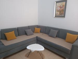 a blue couch with yellow pillows and a white stool at Apartament for Rent Elis in Berat