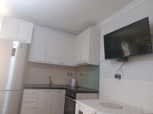 a kitchen with white cabinets and a sink and a refrigerator at Apartament for Rent Elis in Berat