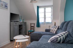 Una sala de estar con un sofá azul y un televisor. en Appartement Ker Glaz, en Damgan