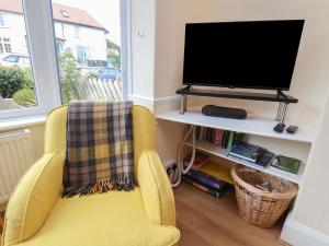 a living room with a yellow chair and a television at Seacliff Cottage in Whitby
