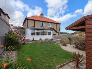 a garden with a lawn in front of a house at Seacliff Cottage in Whitby