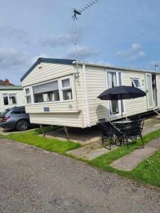 a white rv with a table and an umbrella at 20 Cherry Tree Walk Lyons Robin Hood in in Rhyl