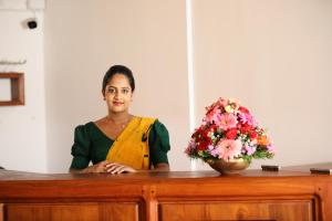 a woman standing behind a table with a vase of flowers at Samudra Villa in Ambalangoda +76 photos