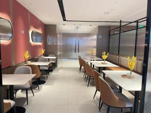a dining room with tables and chairs in a restaurant at Echarm Hotel Guangzhou East Railway Station South China Normal University Metro Station in Guangzhou