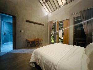 a bedroom with a white bed and a table at Cozy room J in Uluwatu near beach,by d'ulu villa in Uluwatu