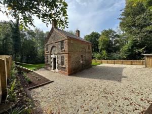 an old brick building sitting on a gravel driveway at Bridge Cottage Upper Malone in Belfast