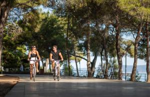 a man and a woman riding bikes down a street at Bluesun Hotel Borak in Bol