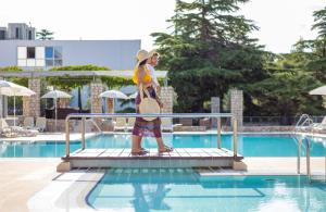 a woman standing on a rail near a swimming pool at Bluesun Hotel Borak in Bol