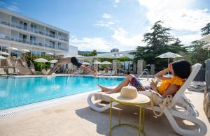 two women sitting in chairs next to a swimming pool at Bluesun Hotel Borak in Bol