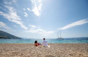 a man and a woman sitting on a beach at Bluesun Hotel Borak in Bol