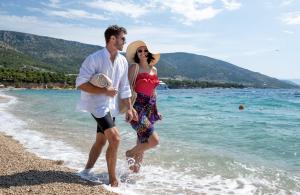 a man and a woman walking on the beach at Bluesun Hotel Borak in Bol