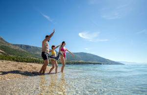 a group of people playing with a kite on the beach at Bluesun Hotel Borak in Bol