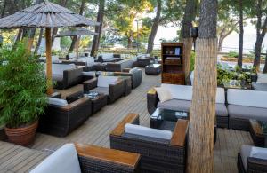 a patio with couches and tables and an umbrella at Bluesun Hotel Borak in Bol