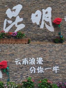 a brick wall with flowers and writing on it at Nostalgia S Hotel Kunming Old Street 时光漫步S酒店 昆明火车北站穿心鼓楼地铁站店 Free fresh ground coffee,Free laundry service in Kunming