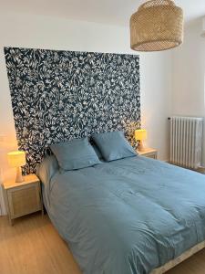 een slaapkamer met een blauw bed en een zwart-witte muur bij Ty Fanch Quiberon in Quiberon