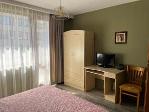 a bedroom with a bed and a desk with a television at Одеса 37 in Sozopol