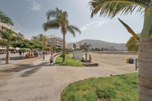 a beach with palm trees and people walking down a sidewalk at Apto Tomasol in Los Cristianos