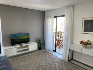 a living room with a television on a white cabinet at RCM Vilas - Apartamento 505 in Joinville
