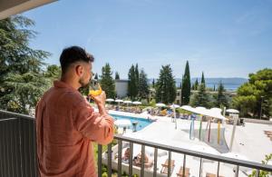 a man drinking a glass of wine in front of a pool at Bluesun Holiday Village Bonaca - Full Board Plus in Bol