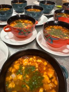 a table topped with bowls of soup on plates at Cob Village - Casute din lut, self check-in, experienta in natura in Berca +26 photos