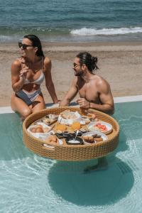 two women and a man sitting in the water with a tray of food at Marika Hotel in Plataniás