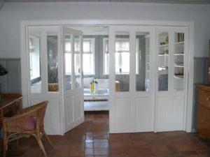 Cette chambre comprend des armoires blanches, une table et une chaise. dans l'établissement Föhrhaus, Einzelhaus, Knickrehm, à Oldsum