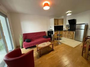 メゾン・アルフォールにあるLa Citadine, Paris à 10 minutes par le Métro 8の赤いソファとキッチンのあるリビングルーム