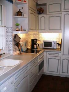 een keuken met witte kasten, een spoelbak en een magnetron bij Hochstieg 36, Feld, Hausteil in Nieblum