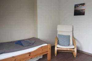 een kleine slaapkamer met een bed en een stoel bij Hochstieg 36, Feld, Hausteil in Nieblum