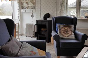 a living room with two chairs and a fireplace at Strandhaus mit Kaminofen Bungalow in Goting