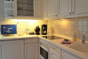 eine Küche mit weißen Schränken und einer Spüle in der Unterkunft Meeresbrise, Whg EG, Otto Guatingwai 18 in Goting