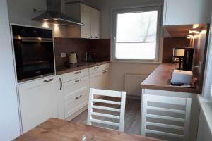 GotingにあるHaus Antje FW Strandlebenの白いキャビネットとテーブルと窓のあるキッチン