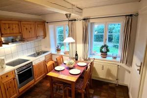 a kitchen with a table and chairs and windows at Skriiwers Hüüs, Hausteil in Alkersum
