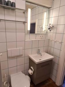 a bathroom with a sink and a toilet and a mirror at Skriiwers Hüüs, Hausteil in Alkersum