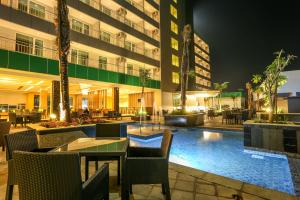 a hotel patio with tables and chairs at night at Dalton Hotel Makassar in Makassar
