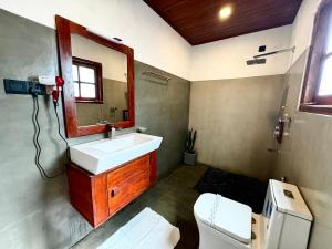 un bagno con lavandino, specchio e WC di The Cottage Sigiriya a Sigiriya