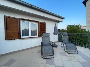 three chairs and an umbrella on a balcony at House Jesenova in Selce