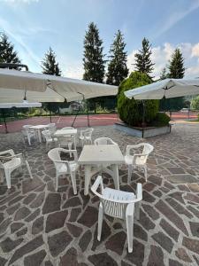 a group of white tables and chairs with umbrellas at Dimora Ludovica in Selvino