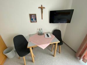 a small table with two chairs and a cross on the wall at Schönstattzentrum Aulendorf in Aulendorf