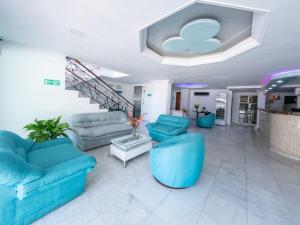 a living room with blue couches and a staircase at Hotel Caribe Plaza Barranquilla in Barranquilla