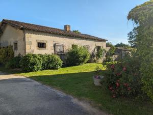 an old stone house with a yard with flowers at Studio Les Granges in Maulévrier