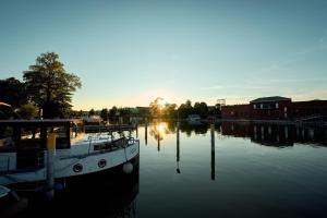 een boot aangemeerd op een rivier met de ondergaande zon bij Gemütliches Wohnschiff in Brandenburg an der Havel