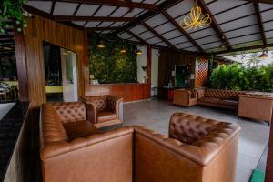a lobby with brown leather couches and plants at Veerdency Luxury Resort - 3 Km to Banglore Airport in Bangalore +40 photos